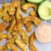 A pile of avocado fries next to halved avocado and a small dish of chipotle mayo.