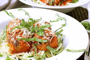 Low Carb Spaghetti and Meatballs with Zoodles. Garnished with freshly grated parmesan and basil.