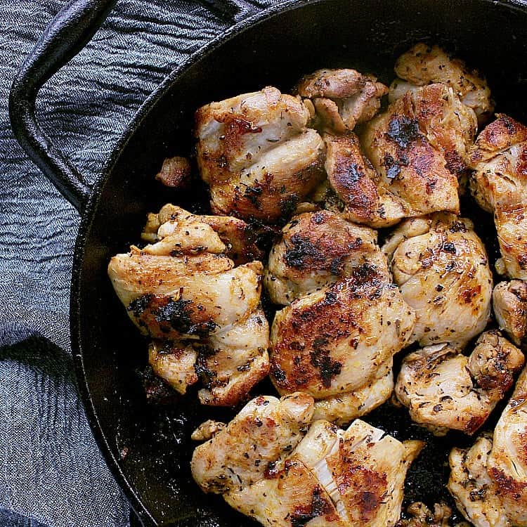 Skillet filled with freshly fried chicken thighs.