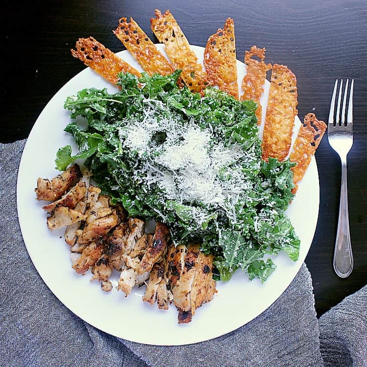 Caesar salad with pan fried chicken thighs, garnished with cheese crisps.