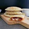 Stack of keto calzones with a half calzone cut in half to show the meat and cheese inside.