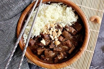 bowl of cauliflower rice and korean beef, garnished with crushed cashews.