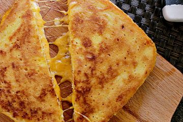 Keto Grilled Cheese cut in half, halves slightly pulled apart to show the melty gooey cheese.
