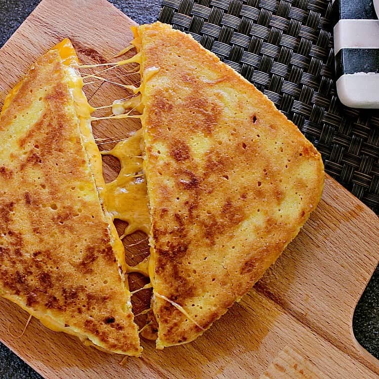 Keto Grilled Cheese cut in half, halves slightly pulled apart to show the melty gooey cheese.