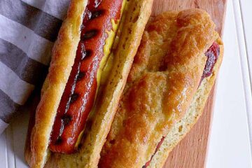 Two hot dogs in keto hot dog buns with ketchup and mustard.