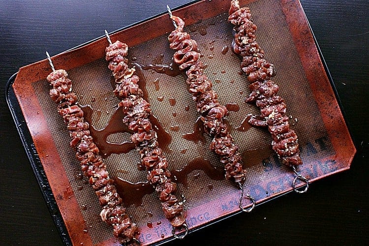 Beef skewers loaded with marinated beef, ready to be broiled in the oven.