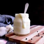 Keto Alfredo Sauce in a jar with a spoon sticking out.