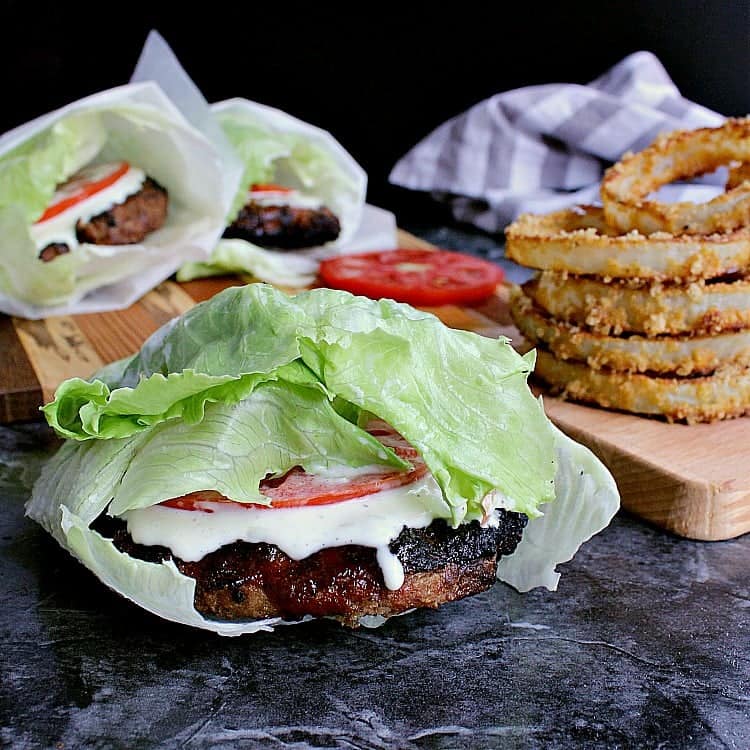 Lettuce Wrapped Burgers with garlic aioli, tomato slices and next to a pile of low carb onion rings.