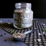 Spoonful of spicy spaghetti seasoning, in front of a jar filled with the spice blend.