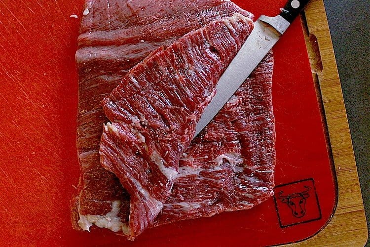 Cutting the flank steal against the grain, horizontally through the steak.