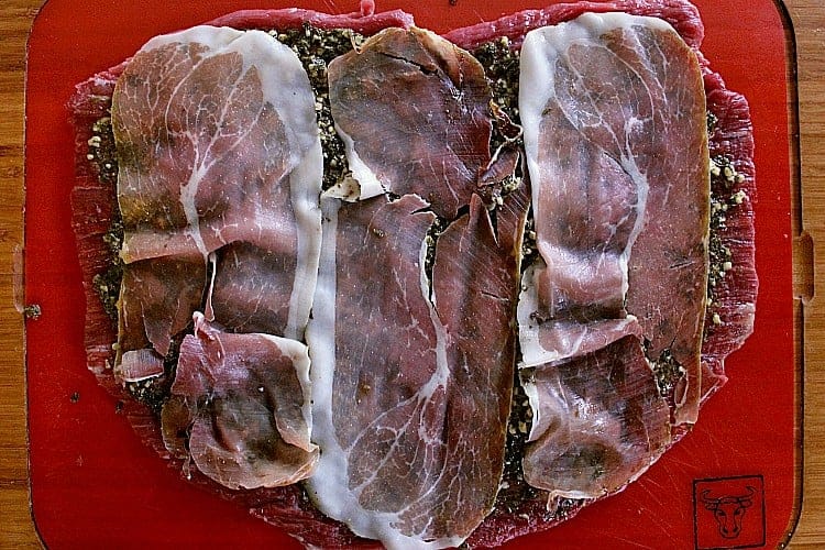Flank steak covered in pesto and prosciutto.