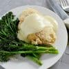 Keto chicken cordon bleu on a plate with garlic sauteéd broccolini and covered with keto cheese sauce.
