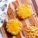 Two keto tuna melts freshly baked, laying on a wooden cutting board.