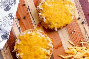 Two keto tuna melts freshly baked, laying on a wooden cutting board.