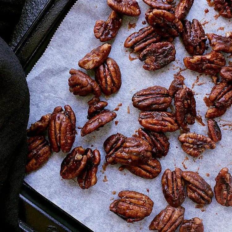 Baking sheet with parchment paper and sugar free candied pecans.