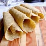 cutting board with 4 rolled up almond flour tortillas.