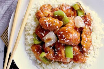 Bowl of keto sweet and sour chicken over a bed of cauliflower rice.