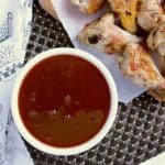 Bowl of keto sweet and sour sauce, next to a platter of chicken wings.
