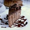 A slice of keto chocolate cheesecake garnished with extra chocolate drizzle and shaved dark chocolate.