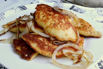 Plate with fried Keto Pierogies and onion.