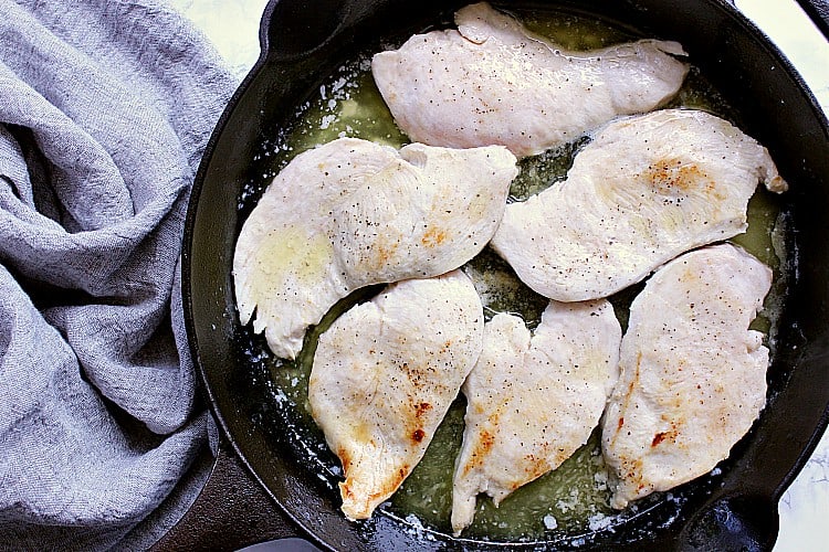Skillet with cooked chicken breasts.