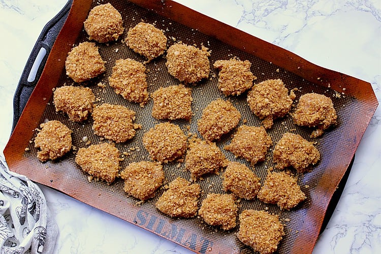 Baking sheet with keto chicken nuggets all breaded and ready for the oven.