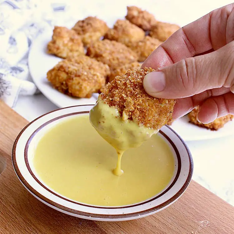 A Keto Chicken Nugget being dipped into a bowl of keto honey mustard.