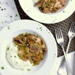 Two white bowls with cauliflower mash, keto beef stroganoff and garnished with fresh parsley.