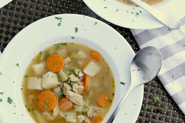 A white bowl filled with Keto Turkey Soup, with a spoon resting on the side.