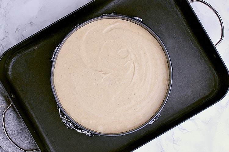 A springform inside a roasting pan, filled with the Keto Pumpkin Cheesecake batter.