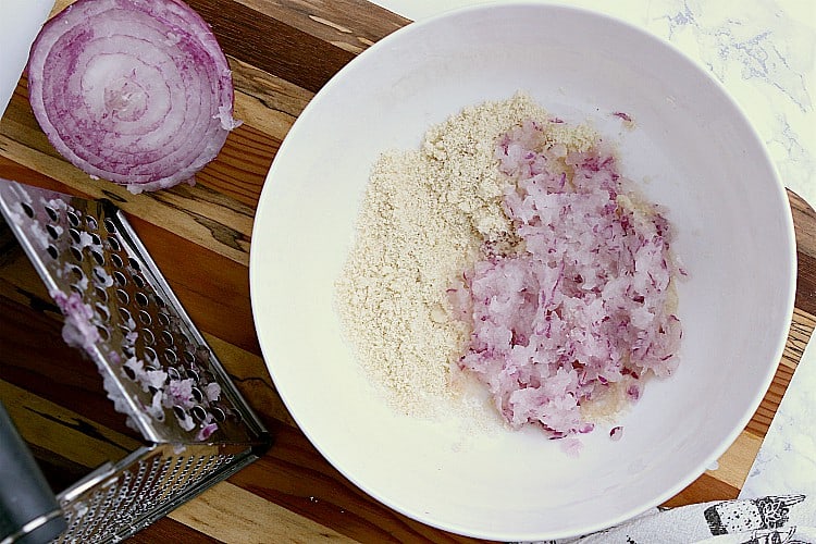 A white bowl with almond flour and grated onion.
