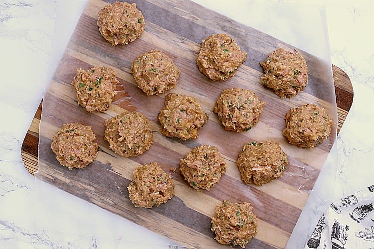 A cutting board with the shaped meatballs.