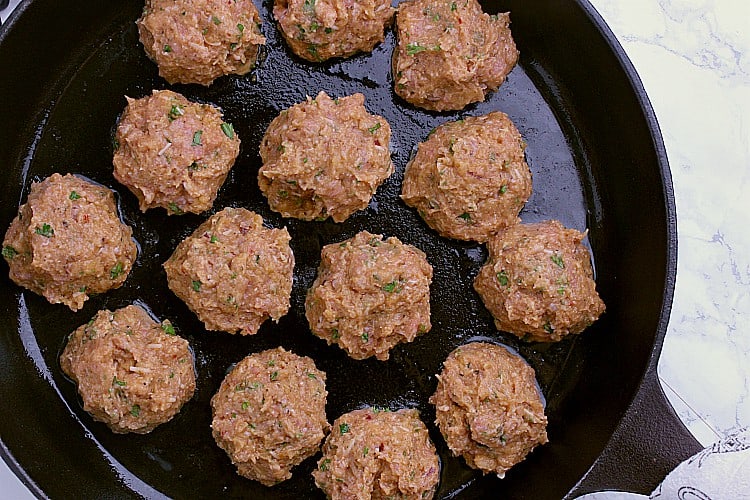 A skillet with the meatballs placed evenly around.