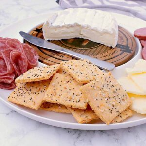 Appetizer plate with brie, cheddar, sausage, salami and a handful of Keto Crackers.