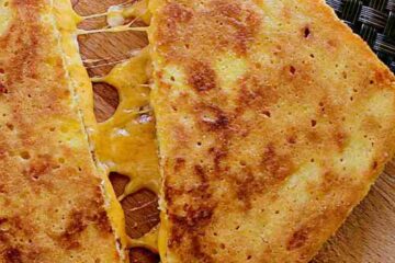 Keto Grilled Cheese sliced in half and slightly pulled apart to showcase the melty cheese.