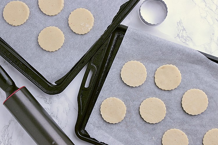 Two baking sheets with the cut out cookies, ready to be baked.