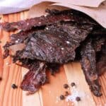 Wooden cutting board with a pile of Keto Beef Jerky.