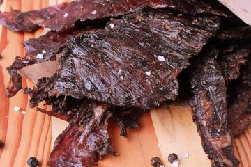 Wooden cutting board with a pile of Keto Beef Jerky.
