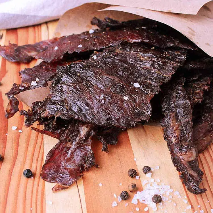 Wooden cutting board with a pile of Keto Beef Jerky.