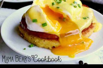 Keto Eggs Benedict on a white plate; the egg has been opened and egg yolk is spilling over the white plate.