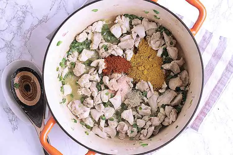 A dutch oven with fried chicken and vegetables.