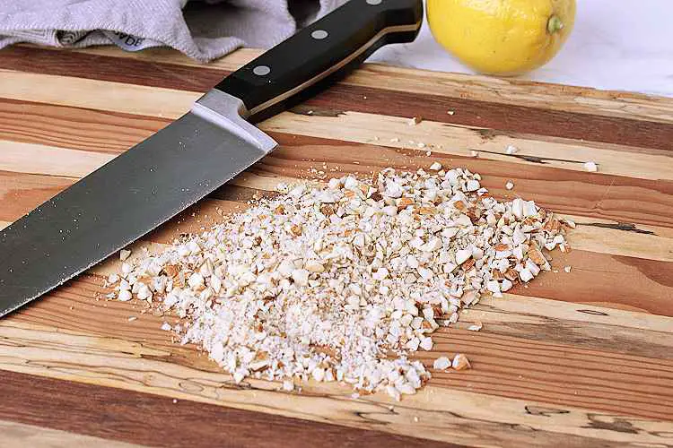 A wooden cutting board with minced almonds
