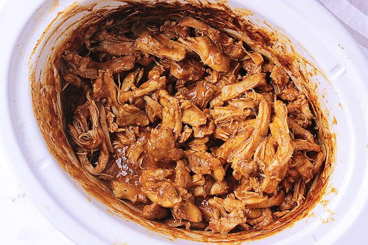 Slow cooker with Keto Pulled Chicken smothered in sauce and ready to be served.