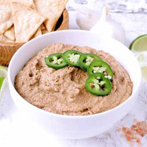 A white bowl with low carb refried beans and jalapeño slices.
