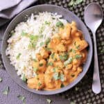 A stone bowl with cauliflower rice and Keto Butter Chicken, beside a spoon.