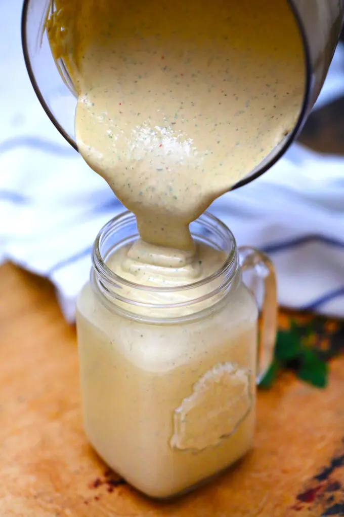 creamy keto sauce being poured into jar