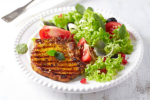 Grilled pork steak with fresh salad White wooden background Copy space